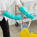 A man wearing green Ansell AlphaTec Solvex gloves is cleaning the floor with a mop.