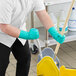 A person in green Ansell AlphaTec gloves mopping a floor.