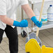 A man wearing Ansell AlphaTec blue rubber gloves and using a mop to clean a floor.
