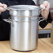A person holding a large silver double boiler.