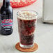 A close up of a glass of IBC Diet Root Beer with foamy bubbles next to a bottle of IBC Diet Root Beer.