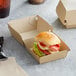 A sandwich in a Sabert paper take-out box with a drink.