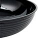 A black Cambro Camwear round ribbed bowl on a table.