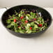A black Cambro round ribbed bowl filled with salad.