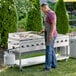 A man using a Backyard Pro stainless steel outdoor grill to cook burgers on a griddle.