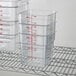 A stack of Cambro CamSquares plastic food storage containers on a wire rack.