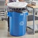 A woman putting a white lid on a blue Lavex recycling can.