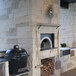 A stone fireplace with a large black Chicago Brick Oven kit.