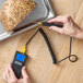 A person using a Taylor digital thermocouple thermometer to measure the temperature of food.