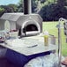 A Chicago Brick Oven Tailgater pizza oven on a table outdoors.