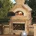 A Chicago Brick Oven wood-fired pizza oven with a shovel leaning against it.