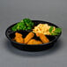 A black Pactiv VERSAtainer round microwavable container with chicken, broccoli, and macaroni.