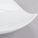 A CAC bone white porcelain peach plate with a curved edge on a gray surface.