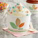 A Bare by Solo leaf print paper food cup of ice cream with sprinkles and a wooden spoon.