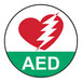 A round white floor sign with a red heart and white lightning bolt and text that reads "AED" in the center.