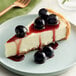 A slice of cheesecake with Luxardo maraschino cherries and berries on top.
