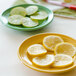 A Tuxton Concentrix saffron china plate with slices of lemons and limes.