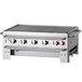 A close-up of a stainless steel Crown Verity portable grill with four burners.
