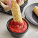 A person dipping a pizza roll into a bowl of Angela Mia pizza sauce.