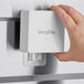 A hand holding a white box with a VersaTile replacement adhesive mounting hanger inside.