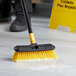 A person scrubbing a floor with a Lavex 10" floor scrub brush.