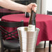 A hand holding a bottle of wine in an American Metalcraft double wall wine bucket.