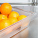 A Carlisle clear plastic food storage box filled with oranges.
