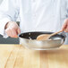 A chef using a Vollrath Centurion non-stick fry pan with a wooden spoon.