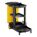 A black and yellow Lavex janitor cart with three shelves and a yellow cover.