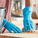 A person wearing Lavex blue latex gloves cleaning a wooden surface.