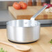 A Vollrath aluminum sauce pan with a wooden spoon inside.