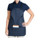 A woman wearing a Chef Revival navy blue apron with a pocket.
