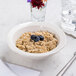 A CAC ivory scalloped edge china bowl filled with oatmeal and blueberries on a white background.