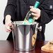 A person holding a bottle of wine in a Vollrath stainless steel wine bucket.