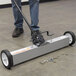 A man using a Vestil aluminum magnetic push sweeper to clean the floor.