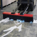 A forklift with a Vestil Forklift Mounted Brush Sweeper attached sweeping up plastic bags.
