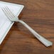 A stainless steel look WNA Comet plastic fork on a plate.
