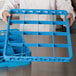 A person holding a blue Carlisle glass rack extender with 16 compartments.