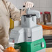 A person using an AvaMix continuous feed attachment to shred carrots.