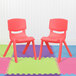 Two red Flash Furniture Whitney plastic chairs on a colorful floor.