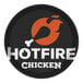 A round black Cambro tray with a white Hot Fire Chicken logo, including a flame and bone.