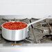A Vollrath Wear-Ever sauce pan with red sauce on a stove.