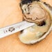 A Victorinox oyster knife with a red handle cutting open an oyster shell.