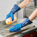 A person wearing blue Showa gloves cleaning a counter.