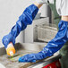 A person wearing blue Showa nitrile gloves cleaning a surface.