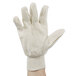 A person's hand holding a white Cordova Premium Ramie / Cotton Blend canvas glove.
