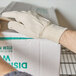 A person wearing Cordova Premium Ramie / Cotton Blend canvas gloves opening a box.