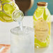 A hand pouring Harney & Sons Organic Lemonade into a glass with ice.