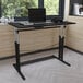 A black Flash Furniture Fairway adjustable height office desk with a laptop on it.