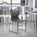 A gray Flash Furniture Hercules chair with a perforated back in front of a white table with black legs.